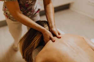 A professional masseuse performing a soothing back massage in a peaceful spa environment.